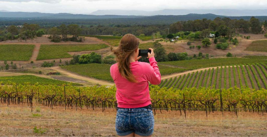 Woman taking photo of vineyards in Australian countryside